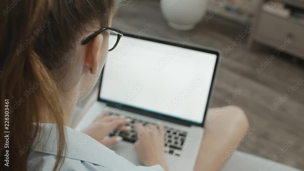 Teenage student girl in glasses works at laptop at home, types text, prepares for exams, studies information on the subject on the Internet Teenage student girl in glasses works at laptop at home, types text, prepares for exams, studies information on the subject on the Internet