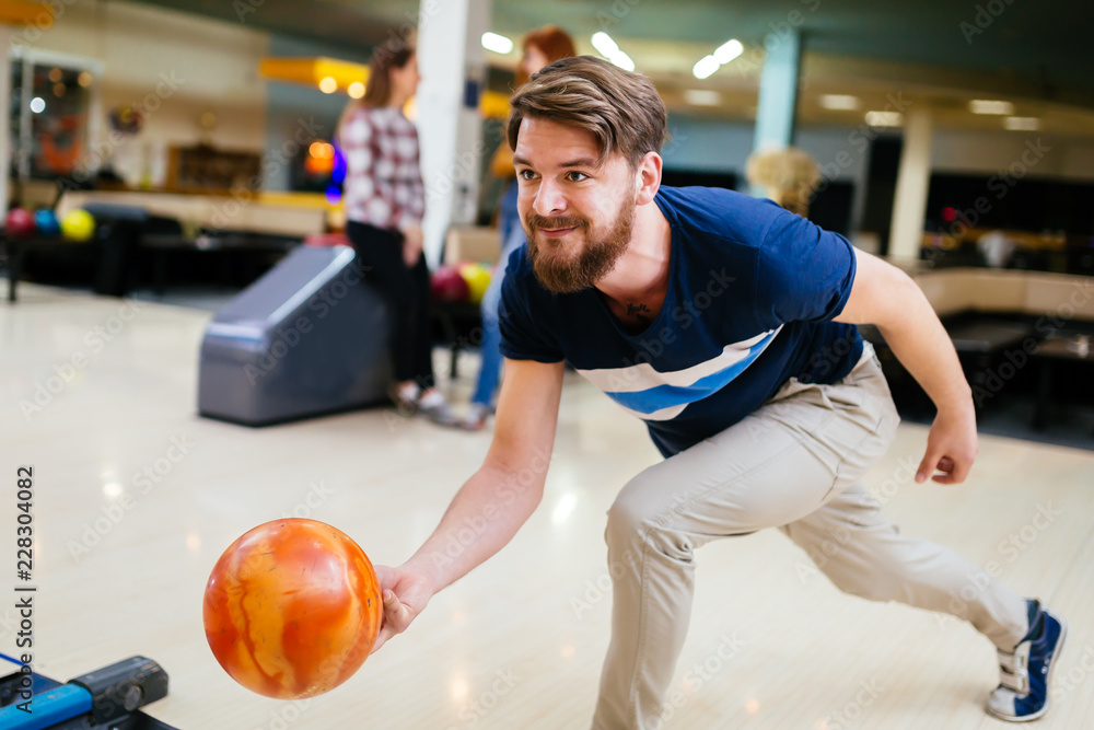 Fototapeta premium Cheerful friends bowling together and having fun