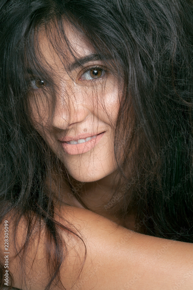 Smiling young woman with hair across her face, close-up. Smiling young woman with hair across her face, close-up.