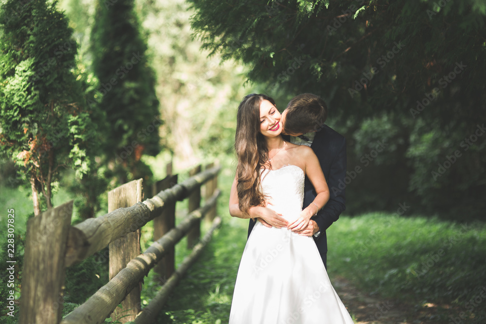 Stylish couple of happy newlyweds posing in the park on their wedding day Stylish couple of happy newlyweds posing in the park on their wedding day