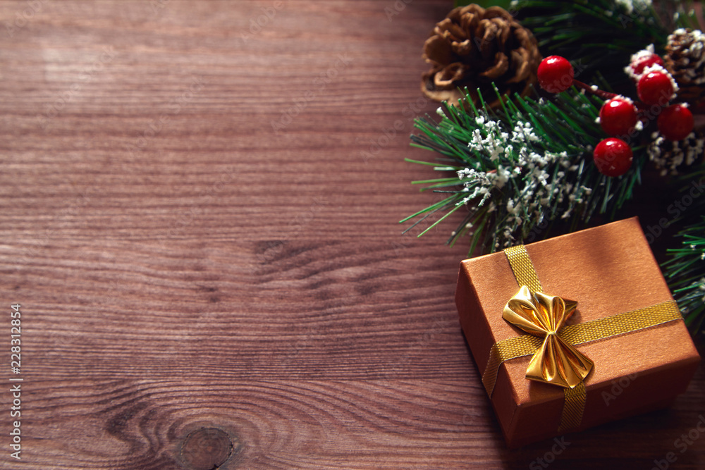 Fototapeta premium Fir tree branches, red berries and present box on wooden surface. Christmas and new year background.
