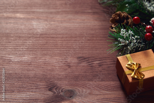 Fir tree branches, red berries and present box on wooden surface. Christmas and new year background.
