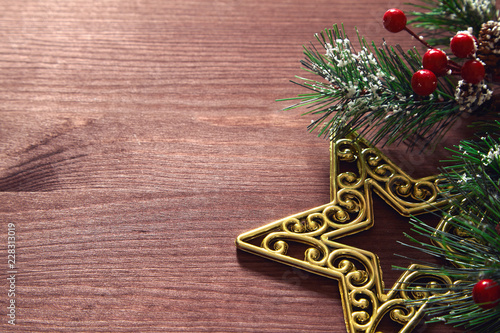 Christmas tree branches, red berries and golden decorative star on wooden background. New year backdrop.