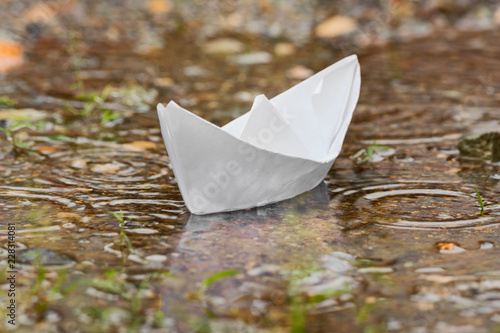 Paper boat in puddle after heavy tropical rain in rainy season monsoon season in Philippines Asia