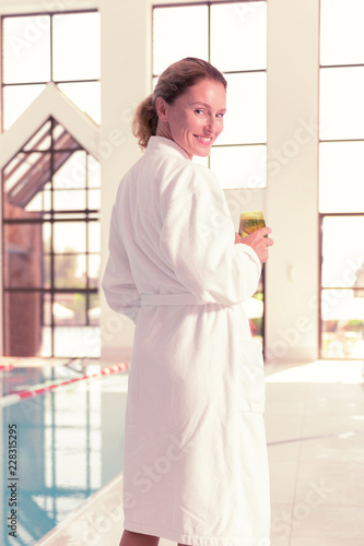 Free Download Spa visit. Cheerful nice woman wearing a white robe while being in the spa - GFXLoad