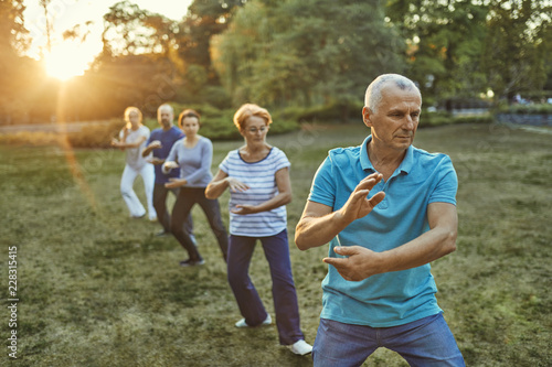 Group of people doing Tai chi in a park photo