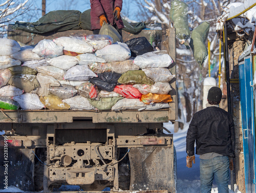 Workers collect garbage in a truck in winter