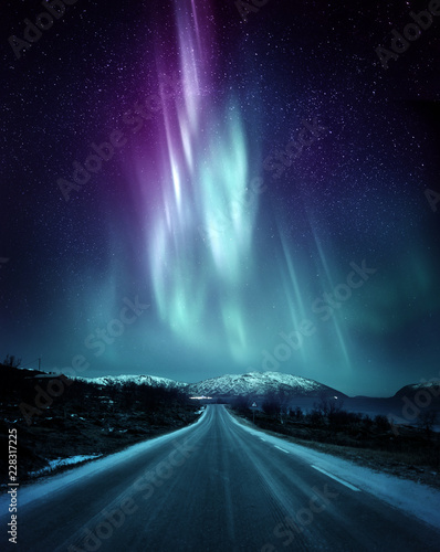 Fotografie, Obraz A quite road in Norway with a spectacular Northern Light Aurora display lighting up the night sky above the mountains