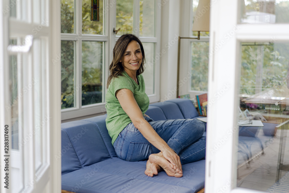 Smiling mature woman sitting on couch at home Smiling mature woman sitting on couch at home
