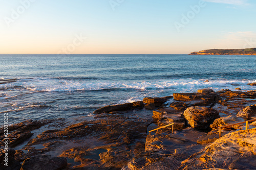 Rocky beach coastline view with clear blue sky.