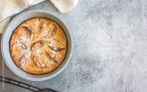 Top view homemade apple pie in baking dish on a dark stone background. Near kitchen appliances. Copy space.