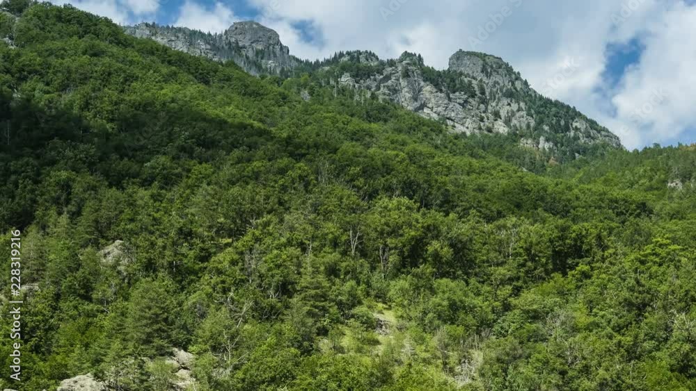 Forested mountainside and rocky peaks - time lapse Forested mountainside and rocky peaks - time lapse