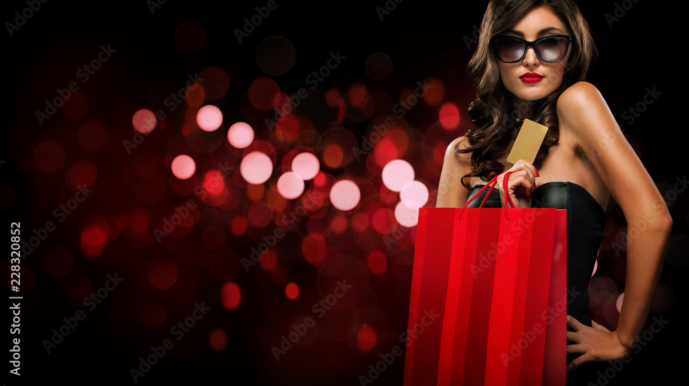 Black friday sale concept. Shopping woman holding red bag isolated on dark background in holiday