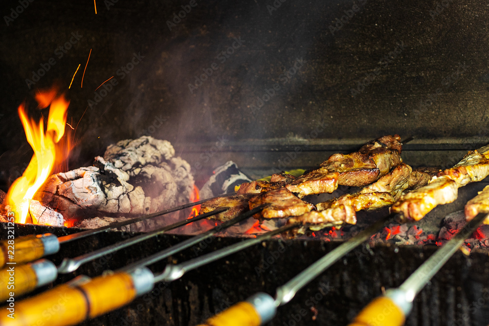 Barbecue in the open air. Shish kebab from pork on coals. Fried pieces of meat on skewers are roasted on a grill. Roasted meat on the fire. Barbecue meat background. Top view. Traditional meat cooking Barbecue in the open air. Shish kebab from pork on coals. Fried pieces of meat on skewers are roasted on a grill. Roasted meat on the fire. Barbecue meat background. Top view. Traditional meat cooking