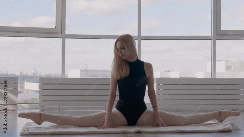 athletic girl stretches on the floor. ballerina sits in cross string and makes bends slowmotion athletic girl stretches on the floor. ballerina sits in cross string and makes bends slowmotion
