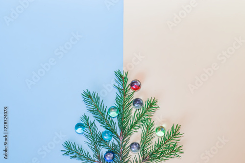 Festive Christmas composition, blue spruce branch with glass balls on pastel background, copyspace 
