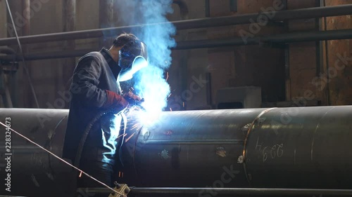 Man welding metal tube with glowing sparks