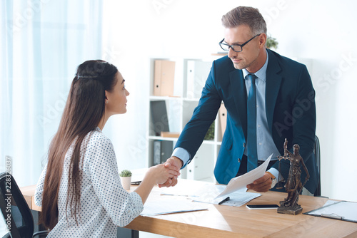professional lawyer and young female client shaking hands in office photo