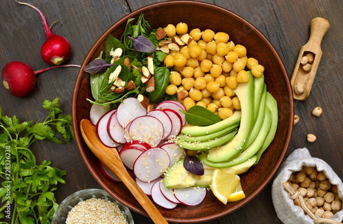 Vegetarian bowl with chickpeas, radish, avocado, herb and seeds,  salad, top view