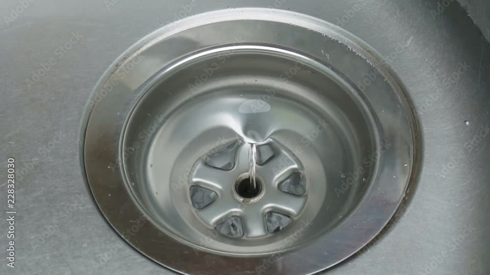 Stainless steel sink plug hole close up with water Stainless steel sink plug hole close up with water