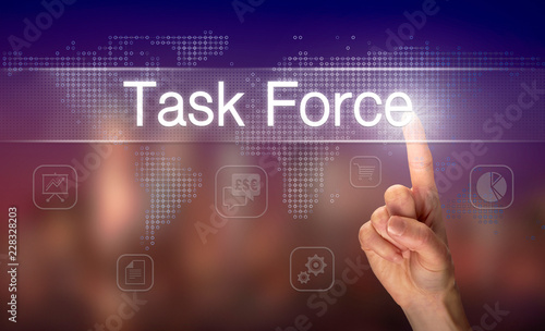 A hand selecting a Task Force business concept on a clear screen with a colorful blurred background.
