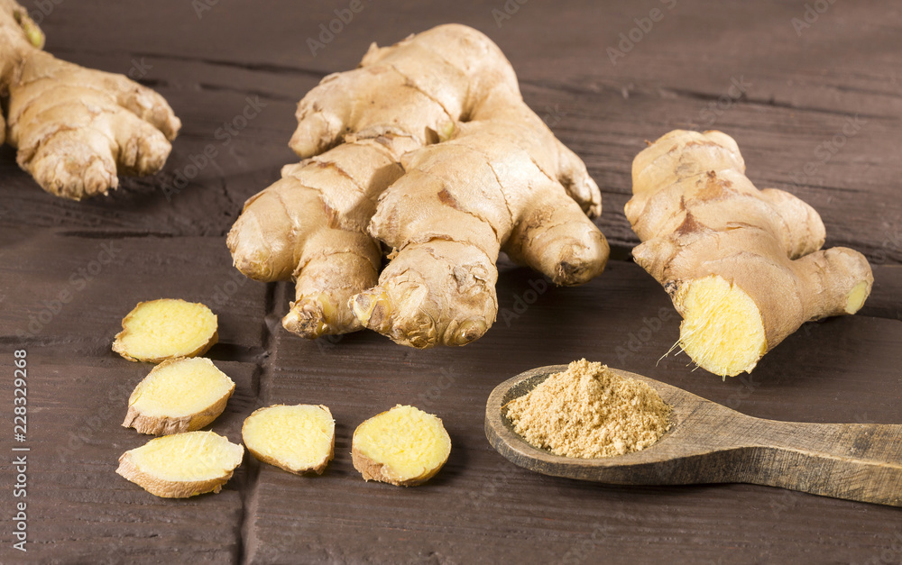 Fresh roots and ginger powder - Zingiber officinale. Wooden background