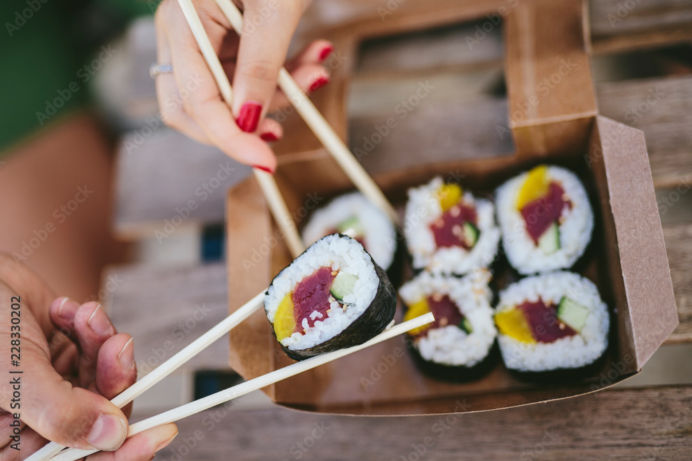 Crop friends eating sushi from box