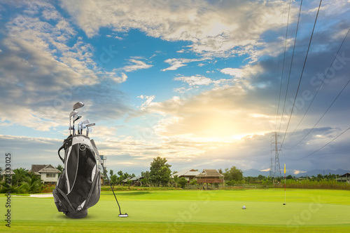 Golf equipment and golf bag , putter, ball on green sunset as background photo