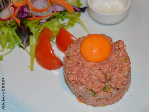 Fresh beef tartar with egg on a white background