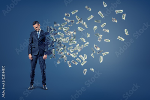Bilde på lerret A sad businessman with head hanging down starts to deteriorate with his body turning into flying banknotes