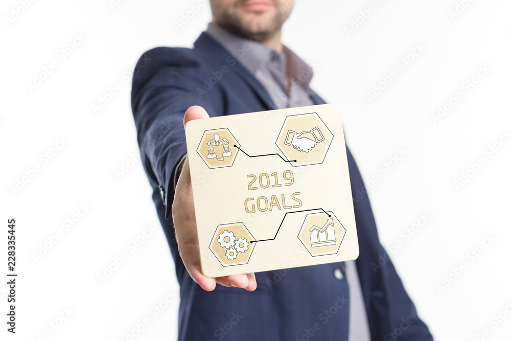 The concept of business, technology, the Internet and the network. Young businessman showing inscription: 2019 goals The concept of business, technology, the Internet and the network. Young businessman showing inscription: 2019 goals