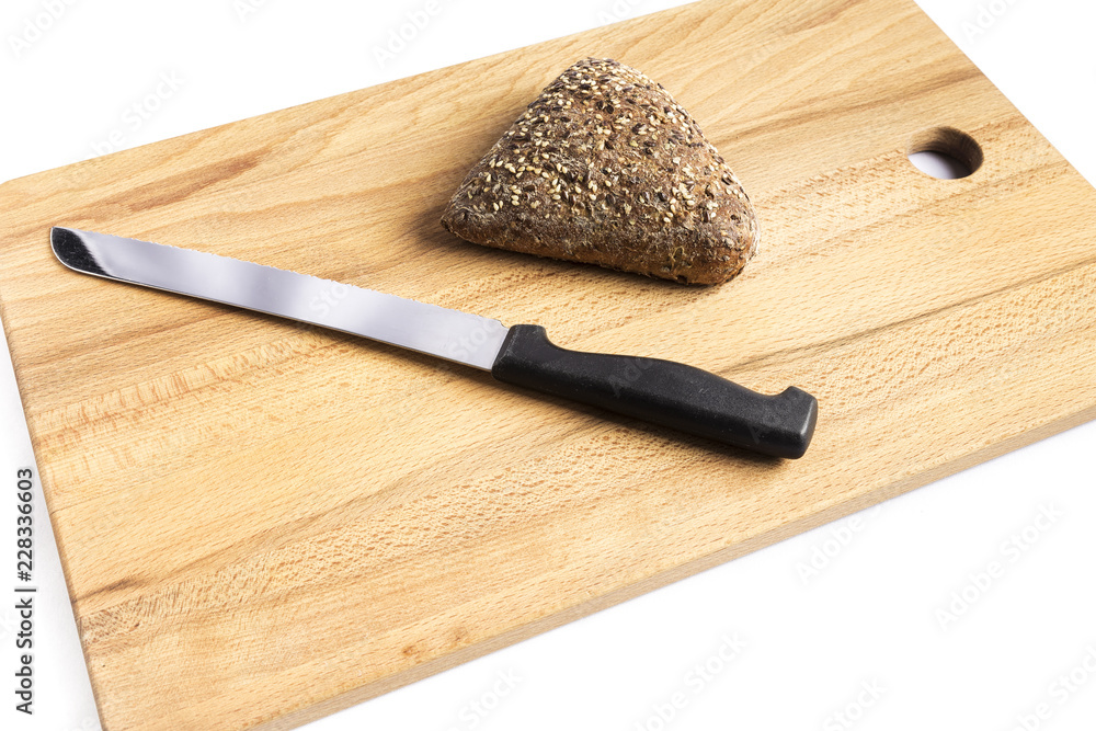 Triangle-shaped wholemeal bread with linseed, oats and sesame seeds next to a knife on a wooden board
