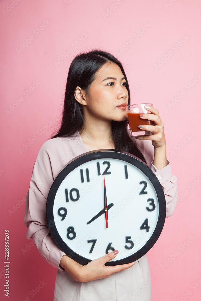Young Asian woman with tomato juice and clock. Young Asian woman with tomato juice and clock.