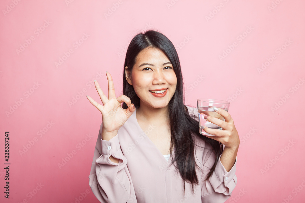 Young Asian woman show OK with a glass of drinking water. Young Asian woman show OK with a glass of drinking water.