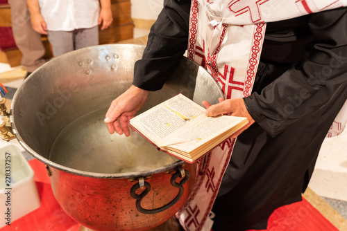 Fototapeta Orthodox priest blesses the water. Baptism ceremony.