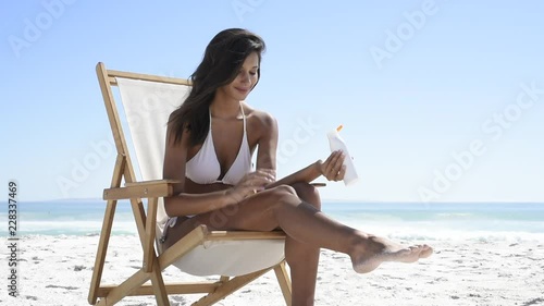 Woman applying suntan lotion at seaside