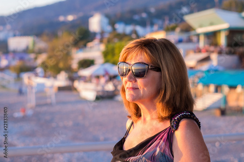 A retired woman enjoying pension at the seaside. A stylish lady watching sunset on a beach.