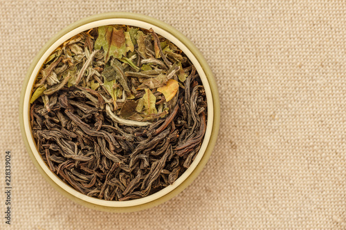 Leaves of black and white tea in a round form on a fabric laid out as a sign of yin and yang