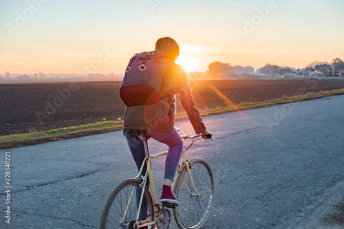 Canvas Print Female commuter riding a bike out of town to a suburban area