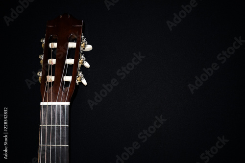 Guitar on black background. Musical hobby. The neck of the guitar. Ukulele. Strings. Musical instruments.