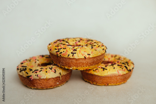 Three yellow donuts biscuits on gray background, beautiful sweet food