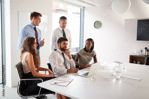 Businessmen And Businesswomen Meeting Around Table In Modern Boardroom