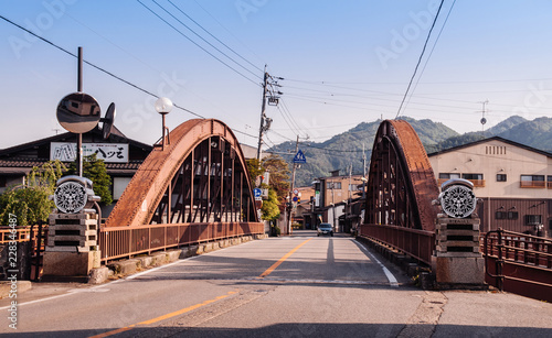 Old houses and historic iron truss bridge over river and mountain view of Hida Furukawa old town, Gifu. Japan photo