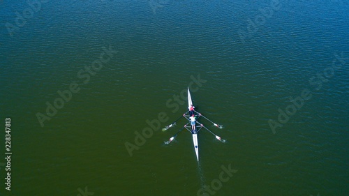 Boat coxed four rowers rowing on the tranquil lake. Aerial view of rowing and rowers.