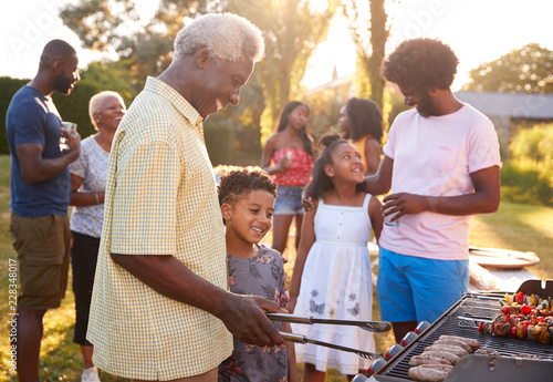 Canvas Print Grandad and grandson grilling at a family barbecue