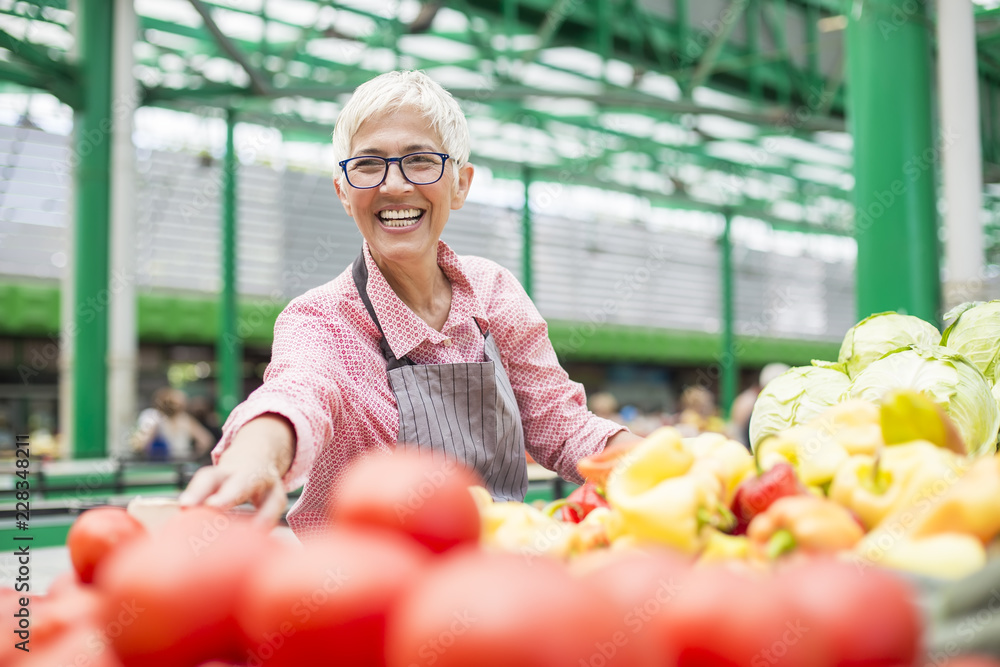 Senior woman sells vegetable on market