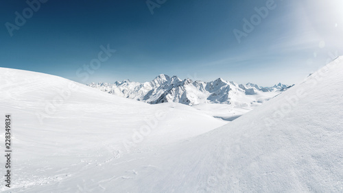 Sun over winter mountains covered with snow. Untouched freeride slope. Snow covered glacier