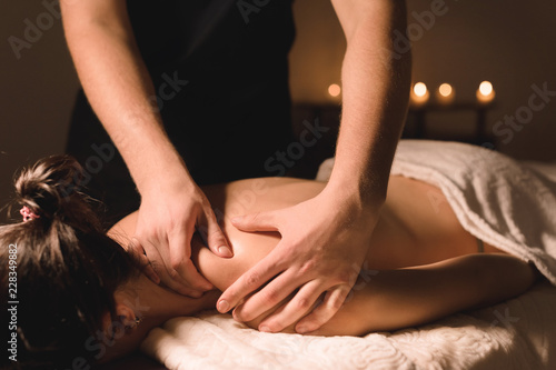 Close up Male manual worker doing spa massage to a young girl in a dark room photo