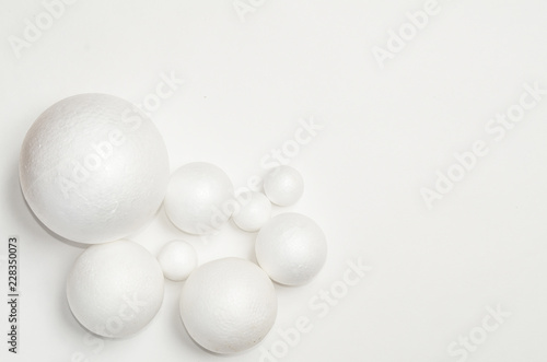 Eight white balls of plastic, of different sizes lie on the plane, on a flat background, in a dense composition, copy space.
