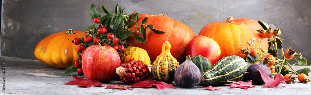 Fototapeta Koncepcja natura jesień. Spadają owoce i warzywa na drewno. Obiad dziękczynny. Śliwki i dynia z słonecznikami i jabłkami.